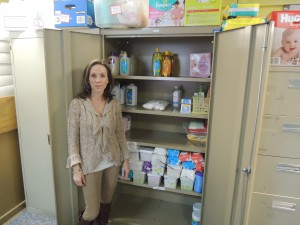 New Life Center’s Maren Henderson standing in front of the cabinet of infant-related lotions and shampoos desperately in need of replenishment.(Photo by Dave Gil de Rubio)