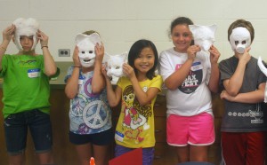 Students display their new masks at Summer Art Adventure camp.